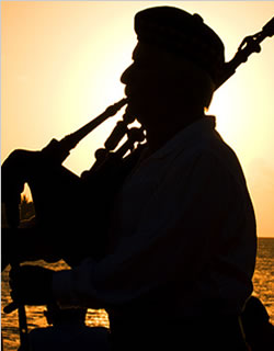 image bagpiper piping at sunset